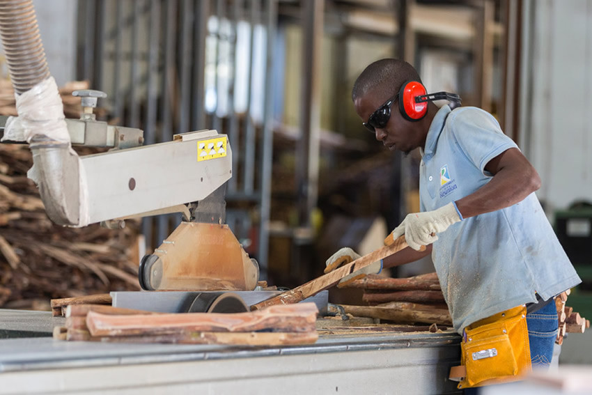 homme qui travaille sur la machine a couper le bois dans l'atelier