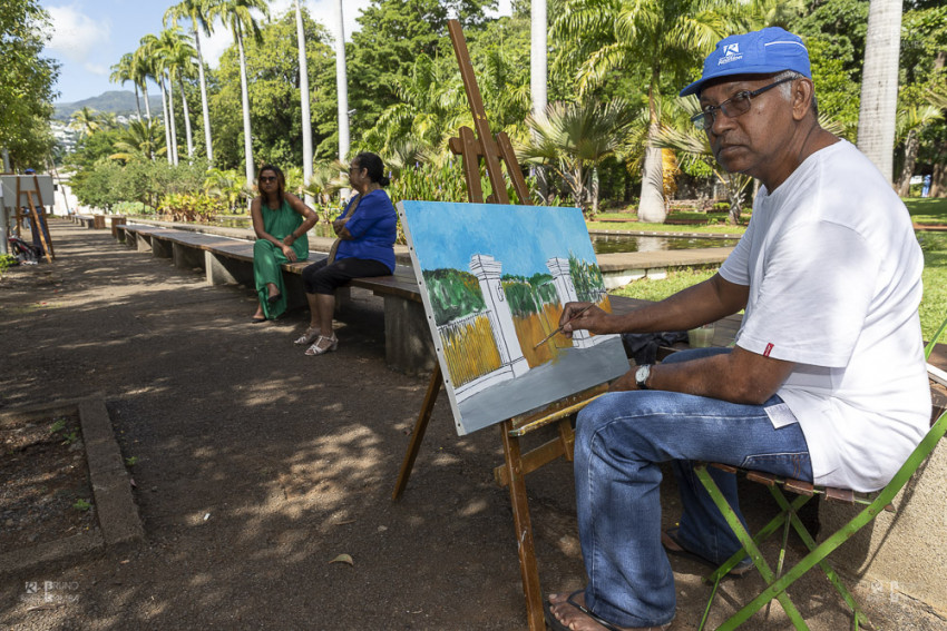 Athanase SITAYA devant son tableau représentant la devanture du Jardin de l’Etat