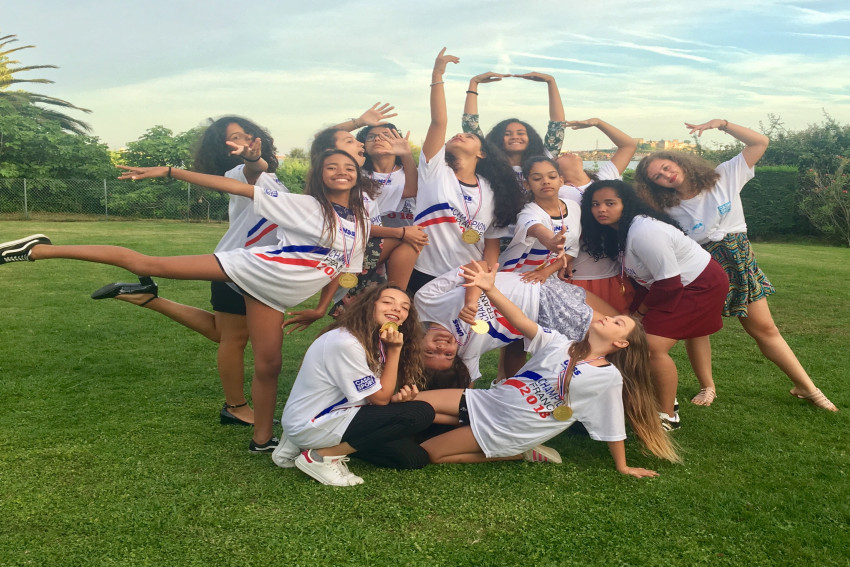 les danseuses font une chorégraphie dans un jardin avec leur médaille d'or autour du cou