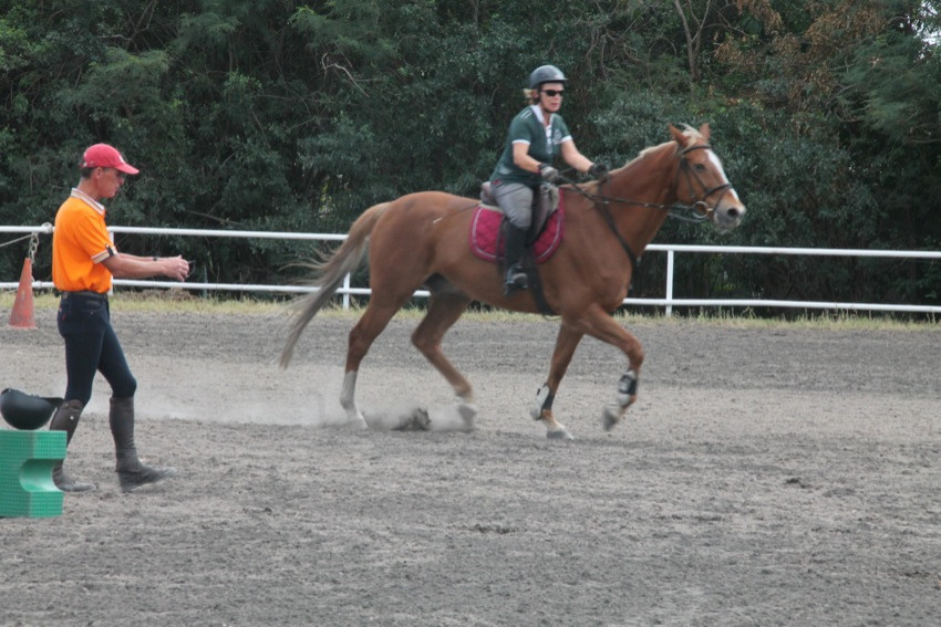 Au milieu du manège, le formateur Pierre de Bastard donne des indications à la cavalière qui est sur son cheval