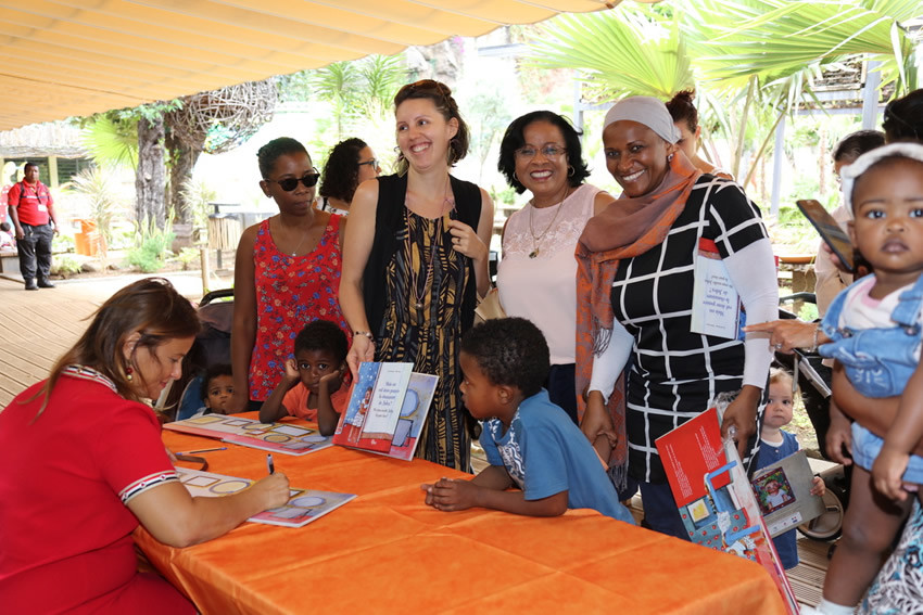 une auteure dédicace ses livres pour les mamans accompagnées de leur enfant