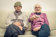 couple de personnes agées dans leur canapé avec la télécommande